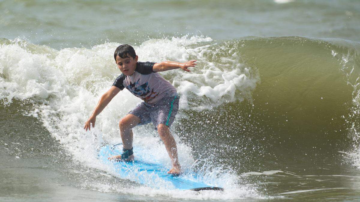 Volunteers with Take A Kid Surfing Day took Giovanni Butler, 9, and dozens of other children out to help him learn to surf on Aug. 7, 2021.