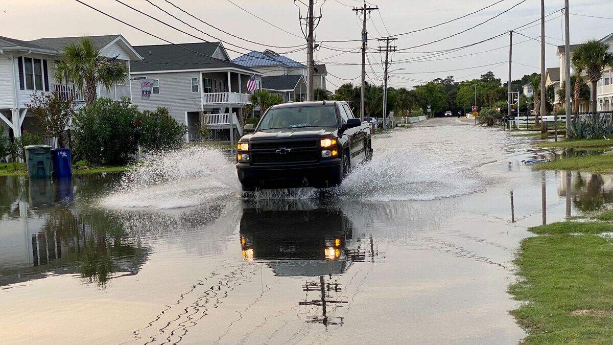 A truck drives through flooding in Cherry Grove as a result of a king tide.