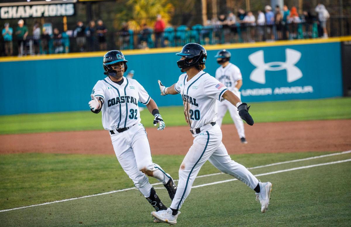 Coastal Carolina’s Eric Brown gets a congratulatory hand slap from Kameron Guangorena after scoring against Kent State. CCU hosted Kent State during the Baseball at the Beach Tournament at Spring Brooks Stadium in Conway on Friday afternoon. February 18, 2022.