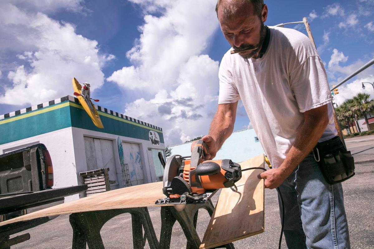Stevie Watts of Watts Produce cuts plywood to cover his shop windows on Main Street in North Myrtle Beach. Locals prepare for Hurricane Florence on Wednesday, September 10, 2018.