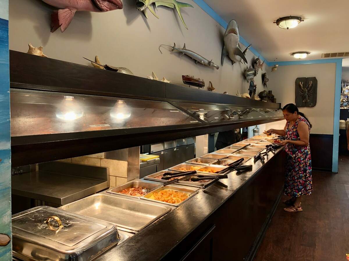A diner fills her plate at the fried fish section of Captain Benjamin’s Calabash Seafood Buffet in Myrtle Beach, SC. Calabash-style fried fish can be found in North and South Carolina and beyond. July 28, 2023.