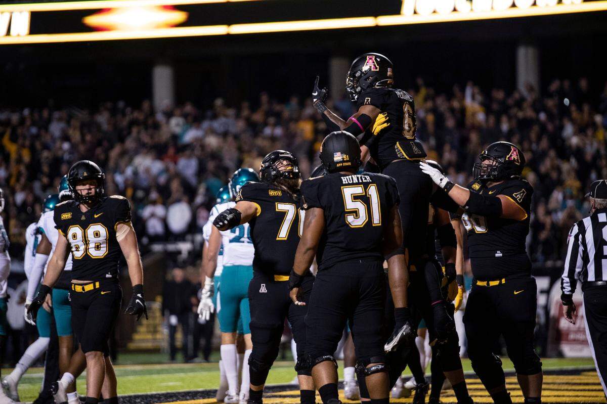 Appalachian State running back Camerun Peoples (6) is hoisted by teammates after his touchdown during the first half of an NCAA college football game against Coastal Carolina on Wednesday, Oct. 20, 2021, in Boone, N.C. (AP Photo/Matt Kelley)