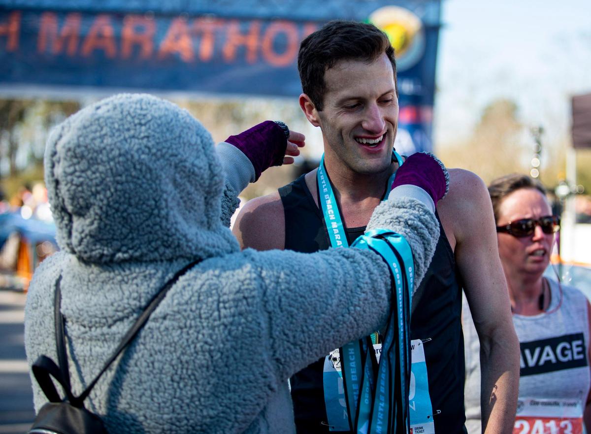 Matthew Leonard of Johnson City, Tennessee, receives his medal after crossing the finish line of the 2020 Myrtle Beach Marathon. Leonard won the race with a time of 2:36:13.