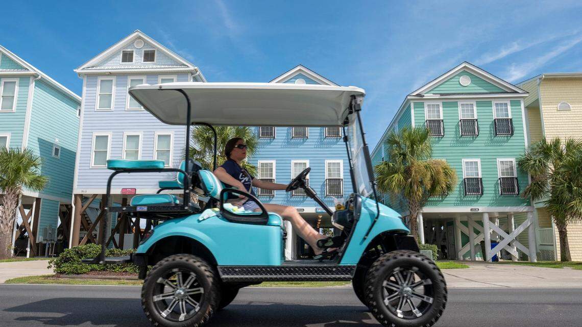 A golf cart passes colorful homes along the Ocean Boulevard in Surfside Beach.