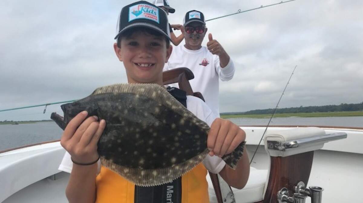 Brewer Cannon shows off a flounder in July 2018 while Capt. Mark Allison of Palmetto Kids Fishing Camp looks on.