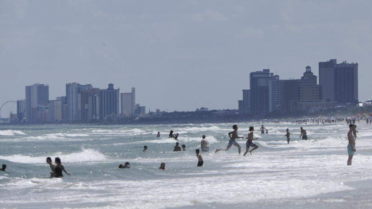 Looking North in the Shore Drive area of Horry County, tourists swim in the Atlantic Ocean as the Myrtle Beach skyline shows in the background. May 29, 2024.