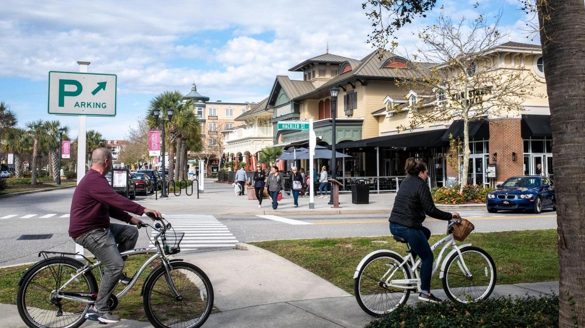 Cyclists ride past the central shopping district in The Market Common community of Myrtle Beach. November 14, 2022.