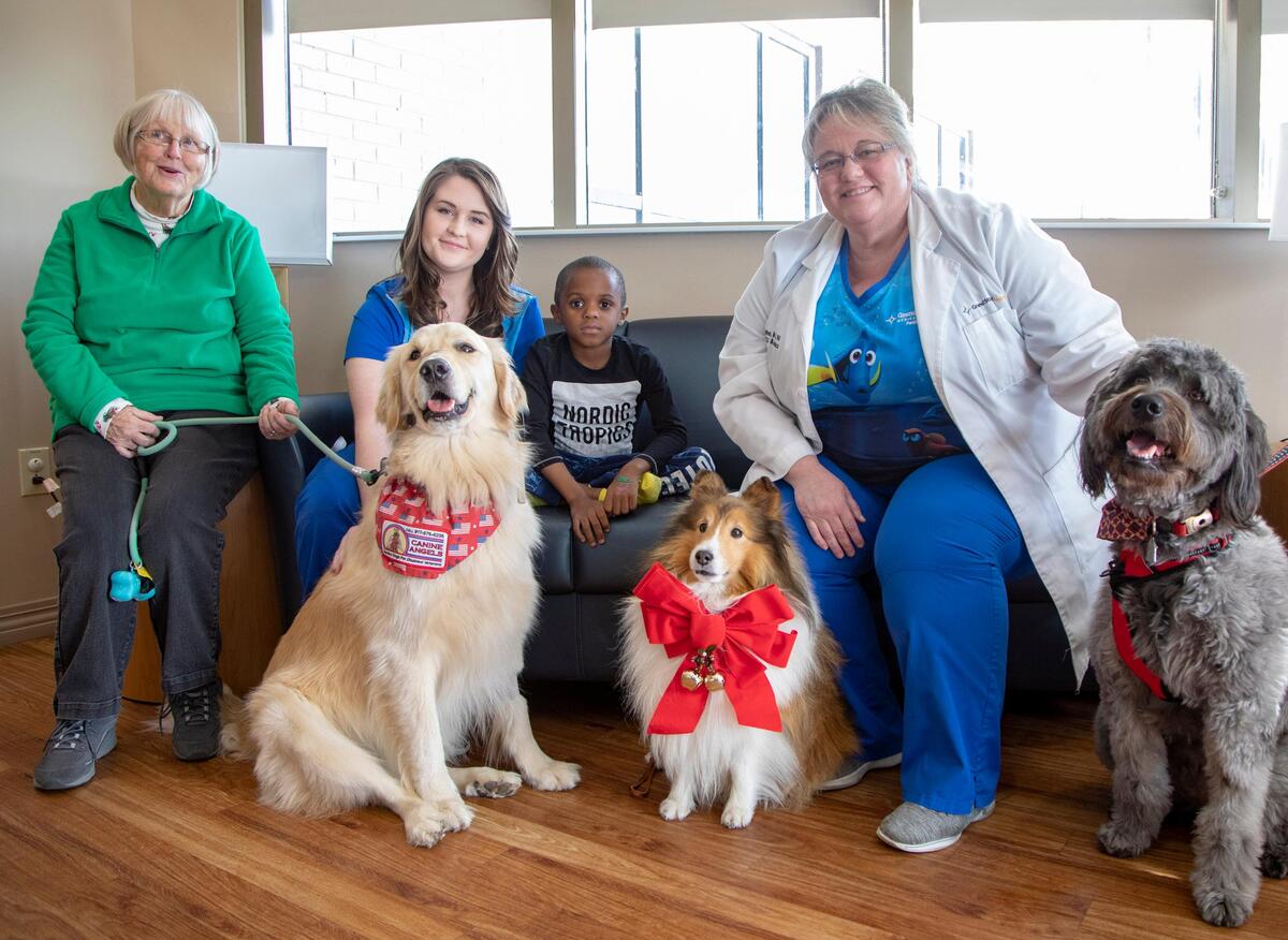 Grand Strand Regional Medical Center Child Life Specialist Taylor Wilson (center) sits with Pet Therapy volunteer Mary Lou Farr (left), Tyler, Pediatric Director Kandi Valentine and therapy dogs (from left) Kula, Chase and Beauregard.