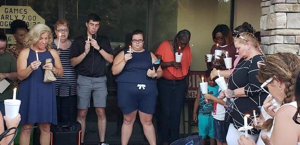 Members of the Johnson family lead a prayer during a vigil at Waccamaw Bingo on July 29. Steve Johnson Sr. and Steve “Sparky” Johnson Jr. were shot and killed during an attempted armed robbery at the hall.
