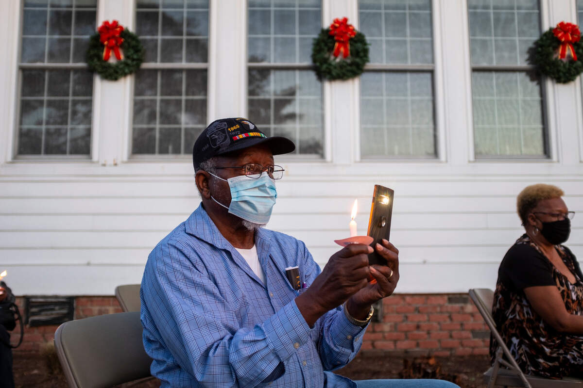 A relative of former student Nina Eaddy films on his phone and holds a candle during the vigil honoring the former students of the Myrtle Beach Colored School.