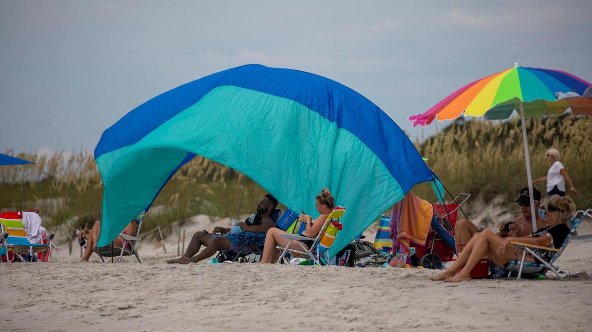 Beach goers sit under a Shibumi Shade at Huntington Beach State Park. July 14, 2022.
