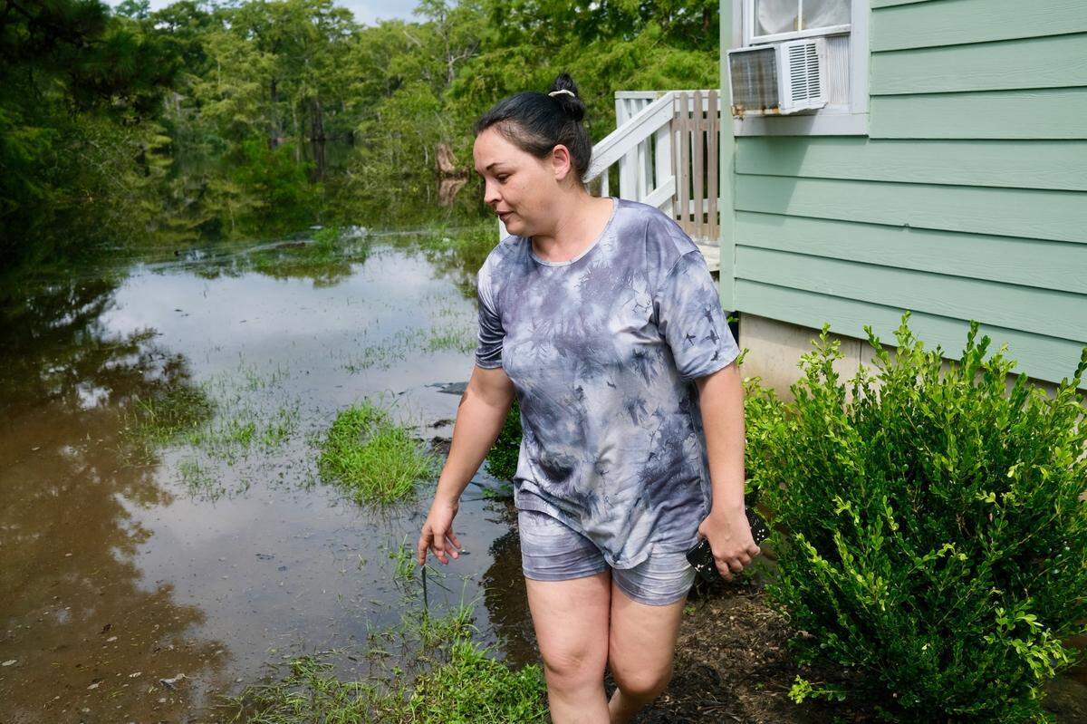 Amanda Watts walks back from her backyard that is slowly flooding. Watts lives along the Waccamaw River and has watched it rise since Tropical Storm Debby arrived the week of Aug. 4. She said she’s worried about her home flooding.