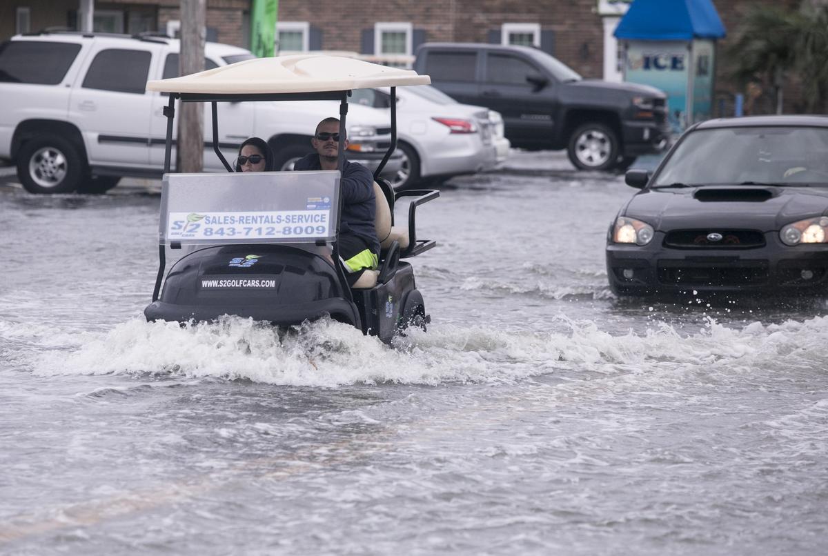 Golf carts and cars pass through flooded streets on Atlantic Avenue in Garden City Beach as the remnants of Hurricane Michael passed through the Grand Strand on Thursday. Oct. 11, 2018