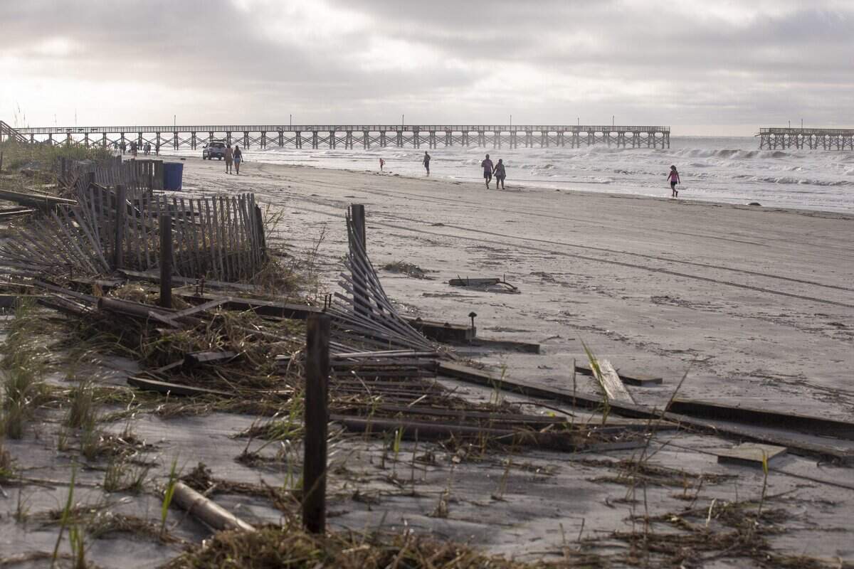 People walk Cherry Grove Point at dawn looking at debris scattered by Hurricane Isaias. Flooding and storm surge from Hurricane Isaias damaged docks in the Cherry Grove area canals and left a debris field on the beach in North Myrtle Beach after a section of pier collapsed and sand dune walkways were destroyed. August 4, 2020.