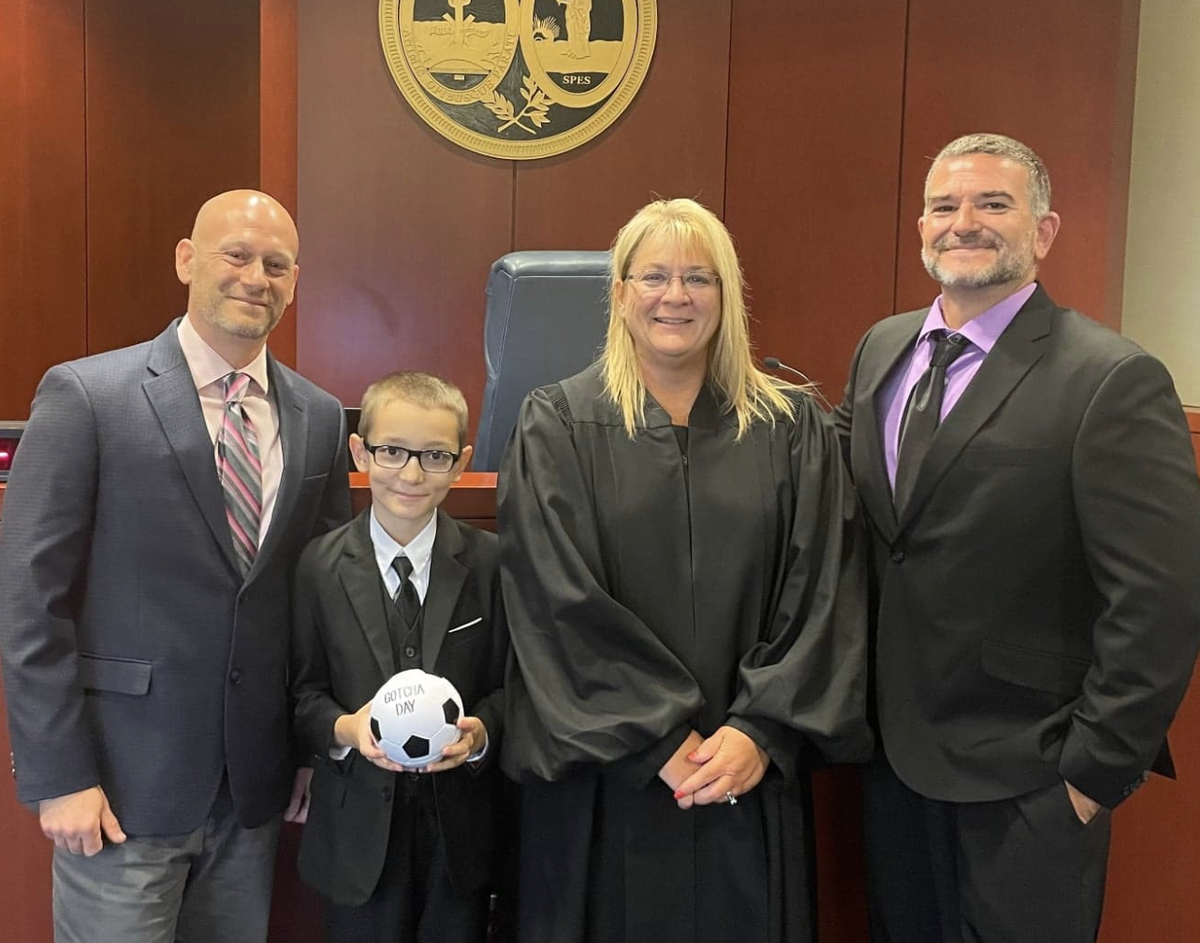 Reece, his dads, and a judge on the day the adoption was finalized.