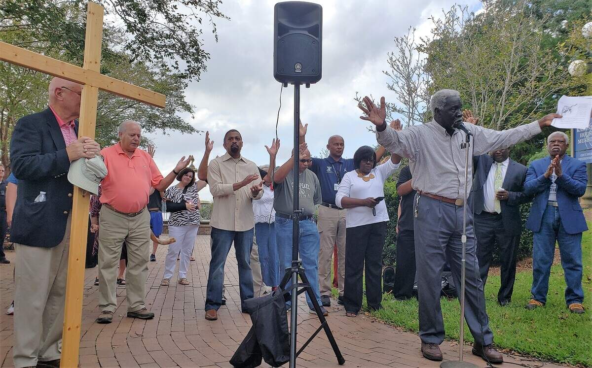 Bishop John Smith Jr. leads a prayer during a service in downtown Georgetown on Tuesday as floodwaters continue to rise