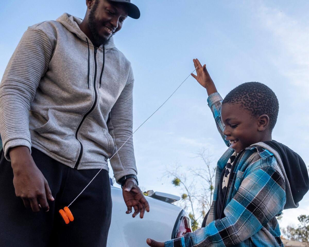 Myrtle Beach High School coach Jeremy Howard teaches Hayden Waldo how to use a yoyo after working with fellow coach Docshee Moore and employees of urban retailer DTLR to hand out Christmas gifts to children as part of an annual grassroots charitable mission.