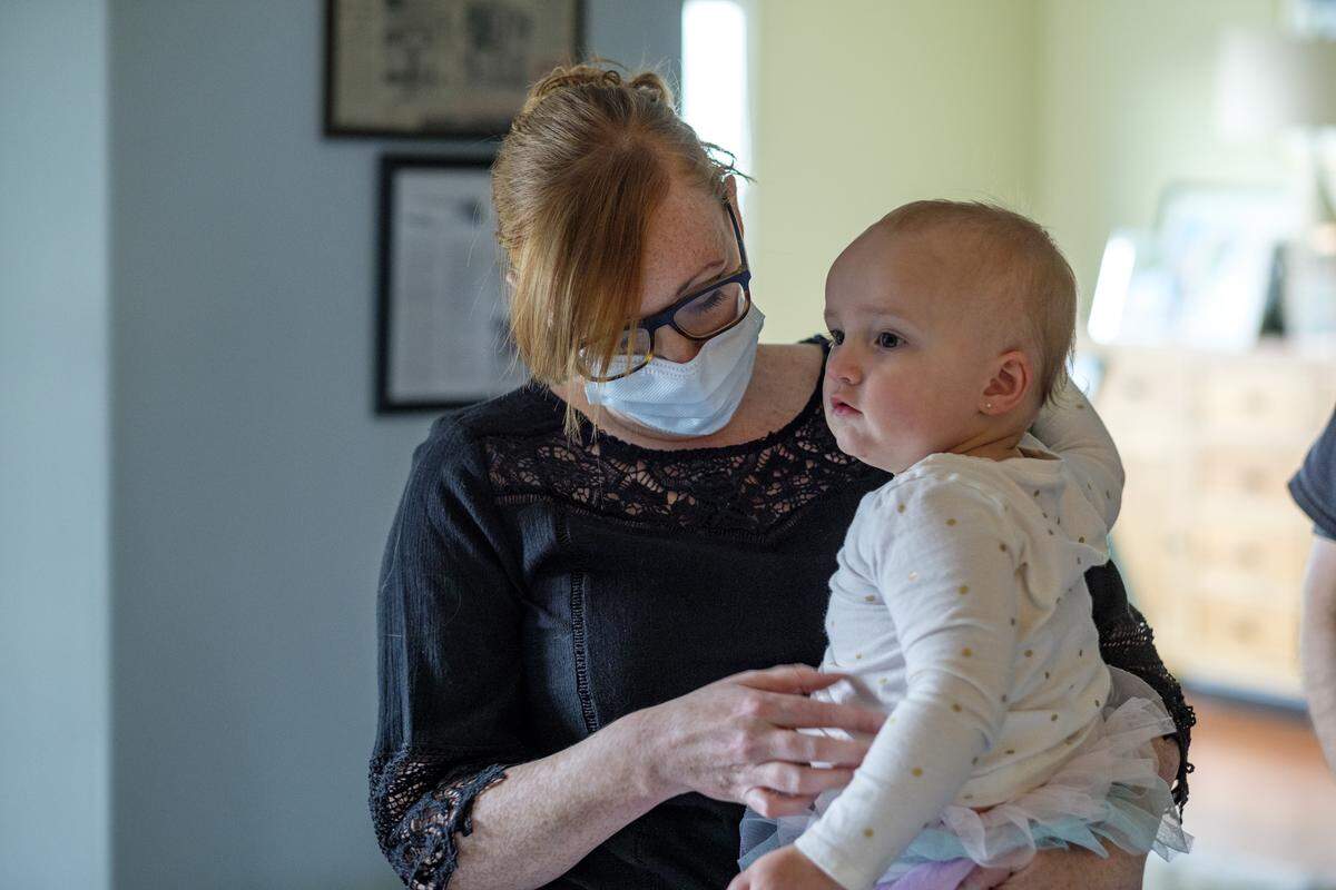 Kelly Hahn, a nurse who works testing patients for coronavirus hold her 2-year-old daughter Ella. When Hahn arrives home, she avoids touching the children until she can get a shower in hopes of keeping her family safe from infection. May 4, 2020