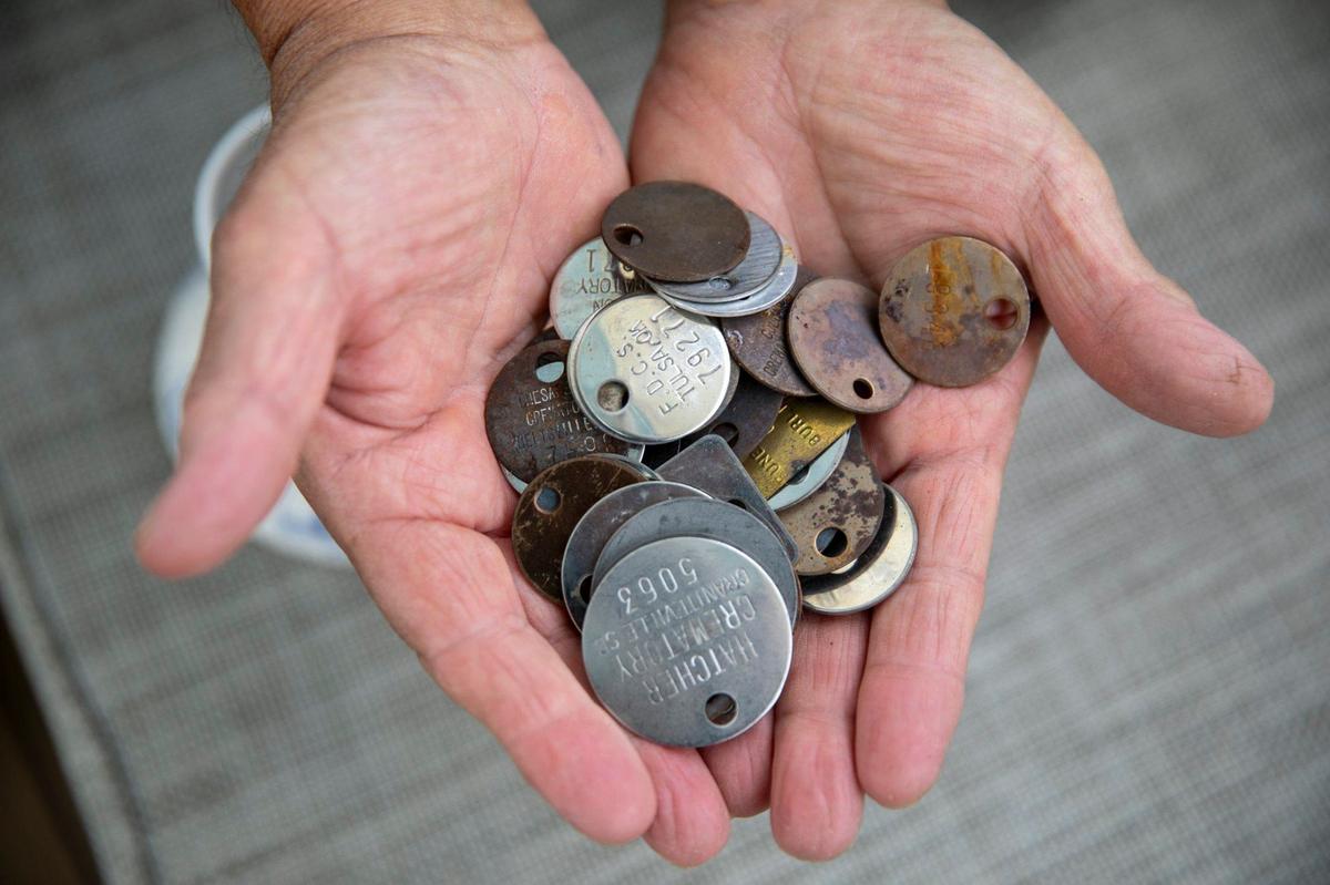 Captain John Jaques holds cremation identification tokens left to him by the families of the deceased. Jaques uses his sailboat “Enchantress” to take families to sea to help spread the cremated ashes of their loved ones. April 26, 2024.
