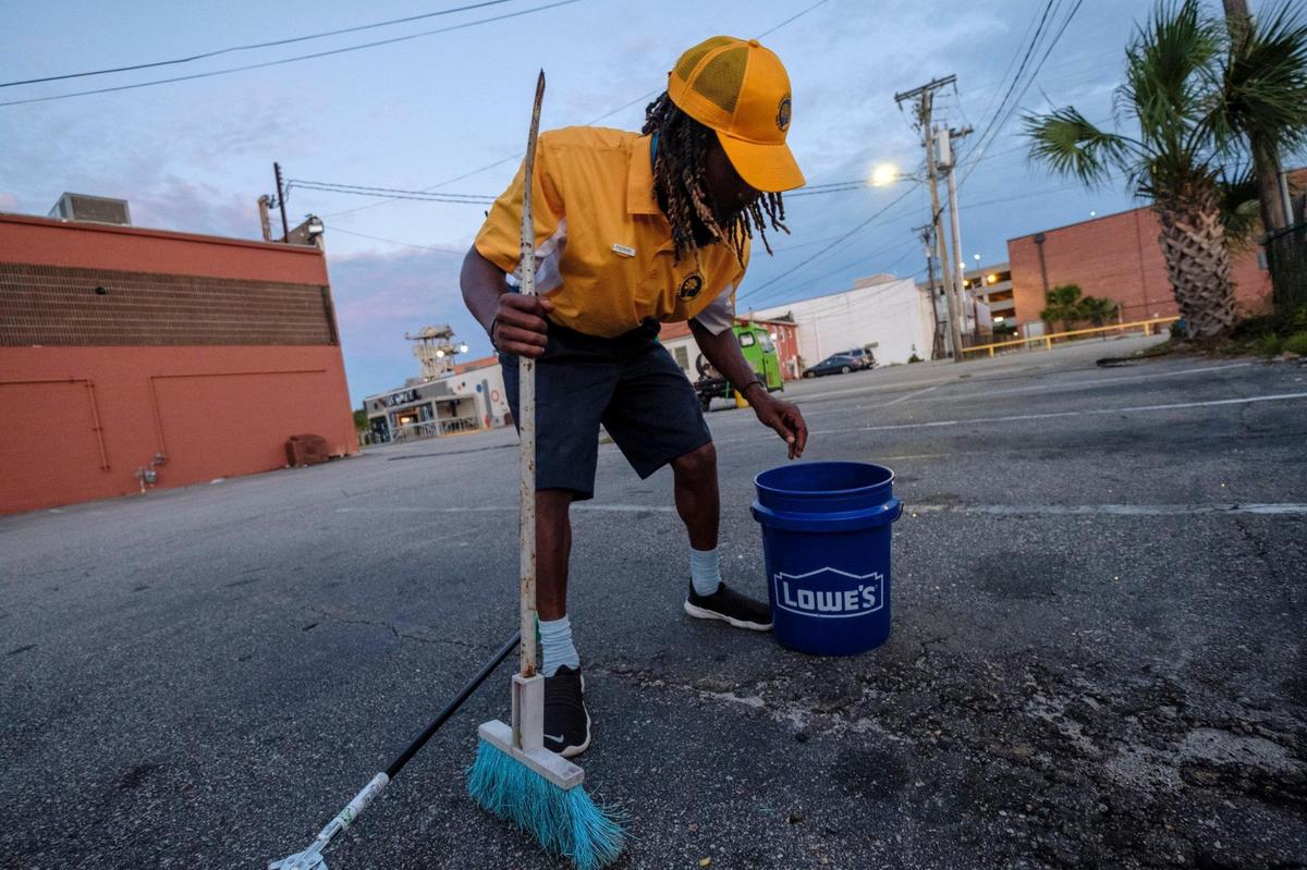 Pierre Owens sweeps up trash left in a parking lot in Myrtle Beach early Saturday morning. Owens is part of a team of a dozen Gold Cap Ambassadors now patrolling the streets of Myrtle Beach cleaning up trash, providing hospitality services, and reporting issues to city officials.The pilot program started in August as a way to improve the safety and cleanliness of the tourism district. August 28, 2020.