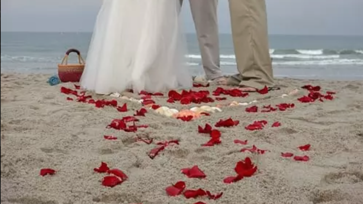 Surrounded by rose petals, a couple gets married on the beach. Beach marriages are becoming more regulated with North Myrtle Beach’s passing of a law requiring wedding vendors to obtain a business license and a beach rental permit.