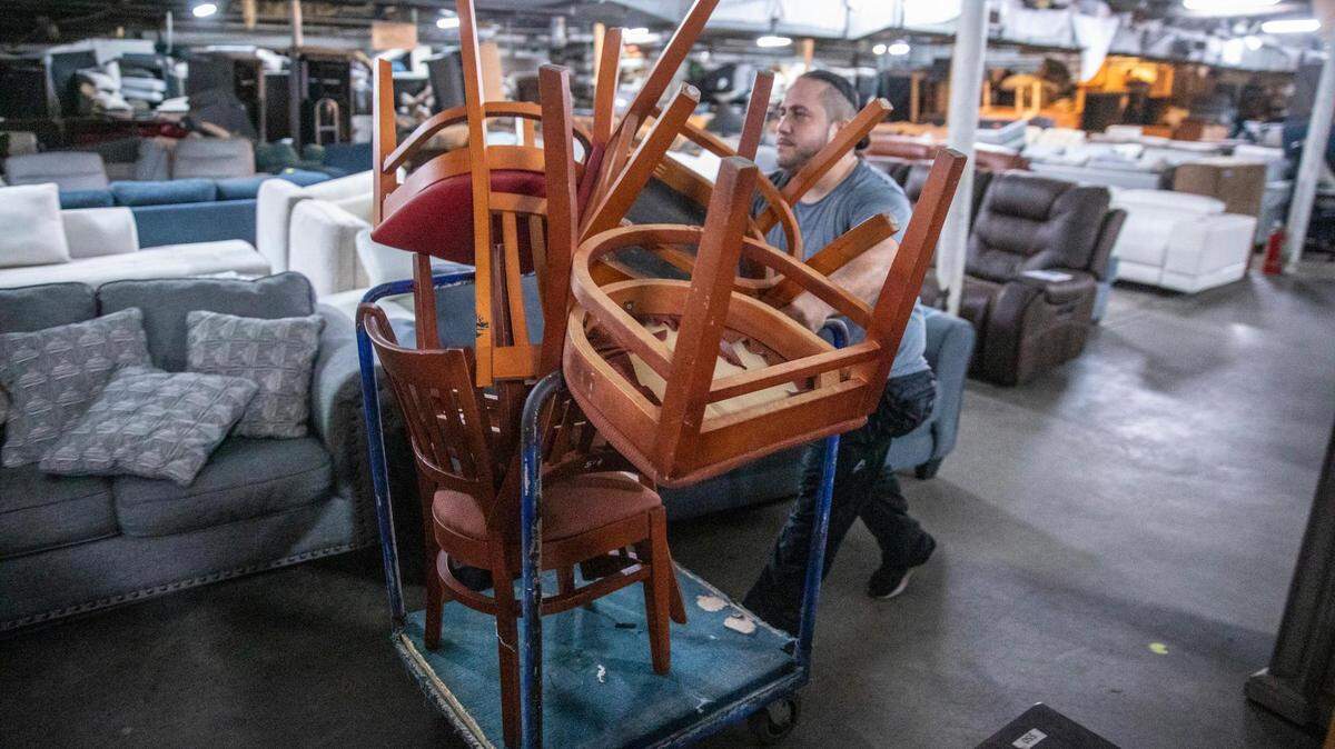 Miguel Rios, an employee at The 16th Avenue Warehouse in Conway, moves a set of dining chairs on the sales floor. The 16th Avenue Warehouse in Conway sells discount furniture, appliances, and home goods including overruns, scratch and dent returns items and second hand hotel furniture. February 23, 2023.