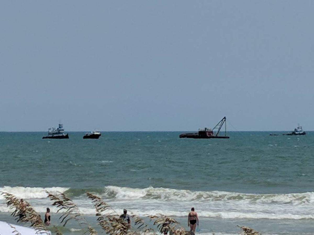 People on the beach watch as the U.S. Coast Guard respond to a capsized barge off Surfside Beach.