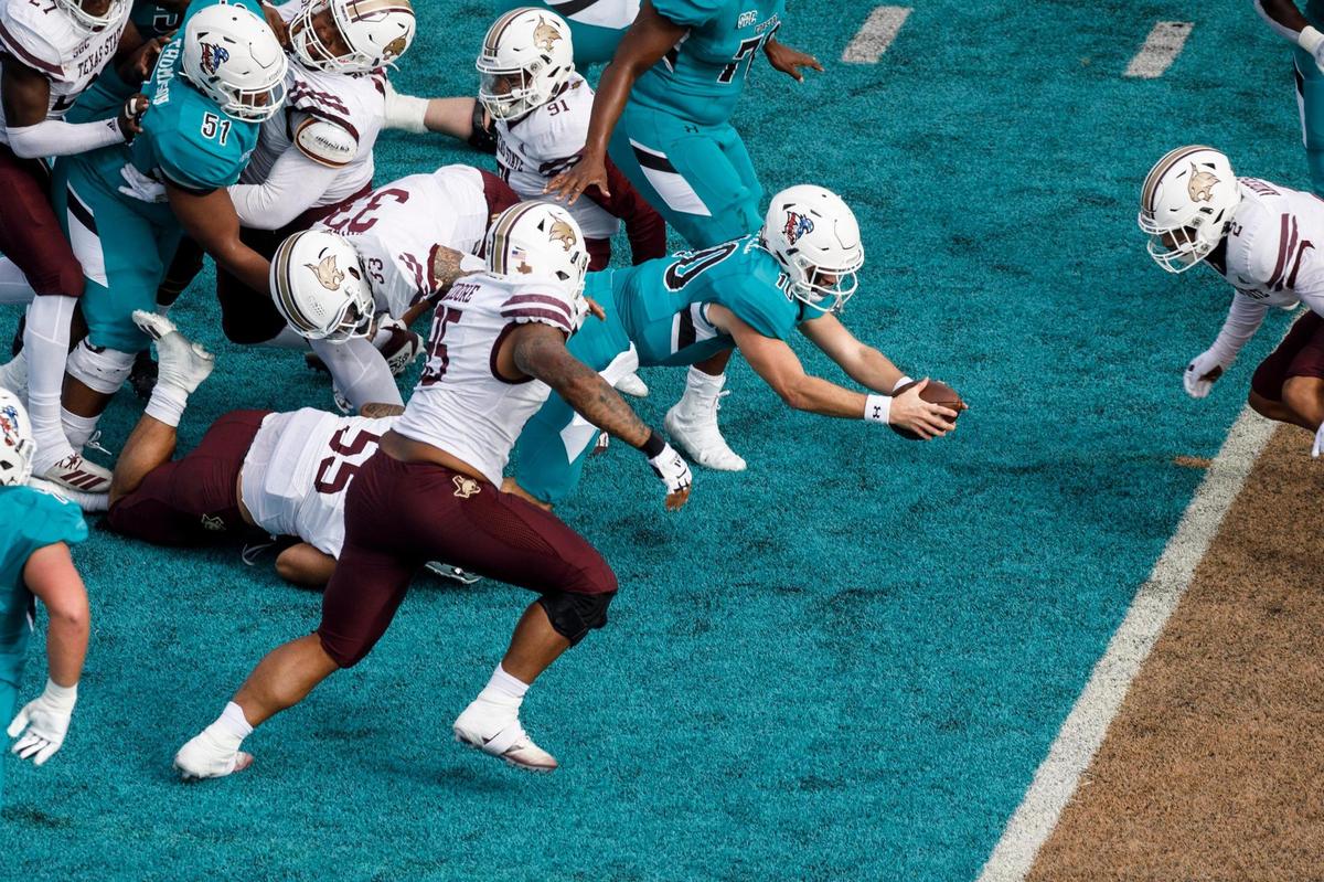 Coastal quarterback Grayson McCall dives for the end zone but is stopped short by Texas State defenders. Coastal Carolina played Texas State in college football. The Coastal Carolina Chanticleers played the Texas State Bobcats in a Sun Belt Conference NCAA FBS college football game in Conway SC. Nov. 20, 2021.