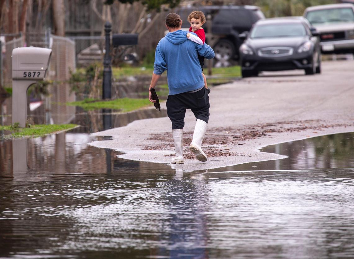 Jon Johnston carries Jaylen Johnsont, age 3, through flooded streets as he removes debris on Rosewood Drive in Socastee. February 18, 2020.