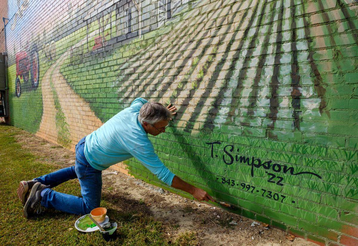 Tommy Simpson, a muralists, paints on the side of a building off Main Street in Loris, S.C. Simpson is known for his large nostalgic murals around the region. October 31, 2022.