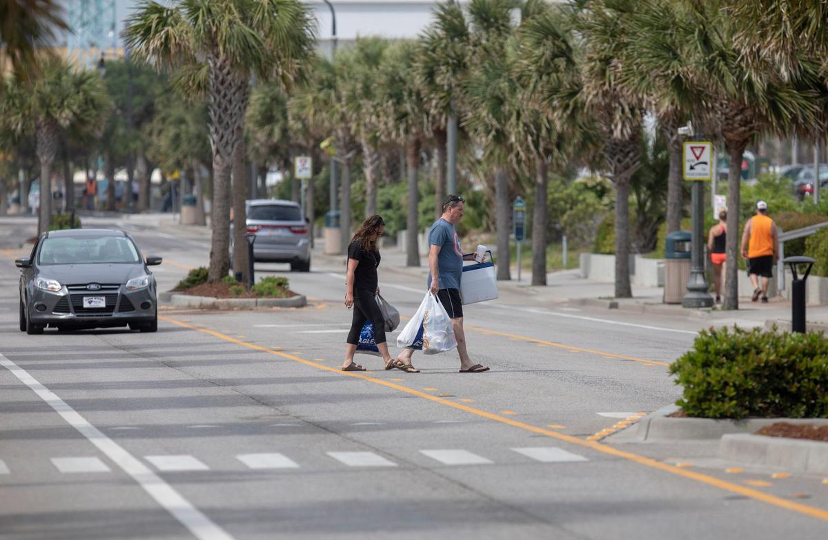A vacationing couple crosses Ocean Boulevard Friday in Myrtle Beach carrying plastic bags.