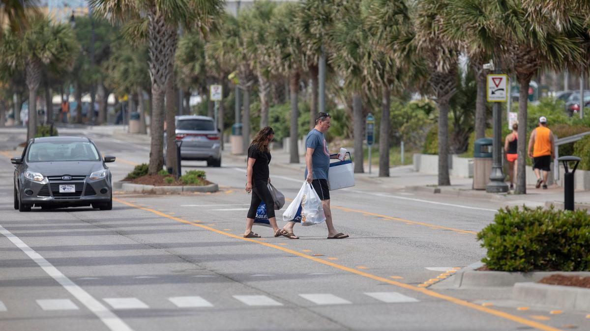 A vacationing couple crosses Ocean Boulevard Friday in Myrtle Beach carrying plastic bags.
