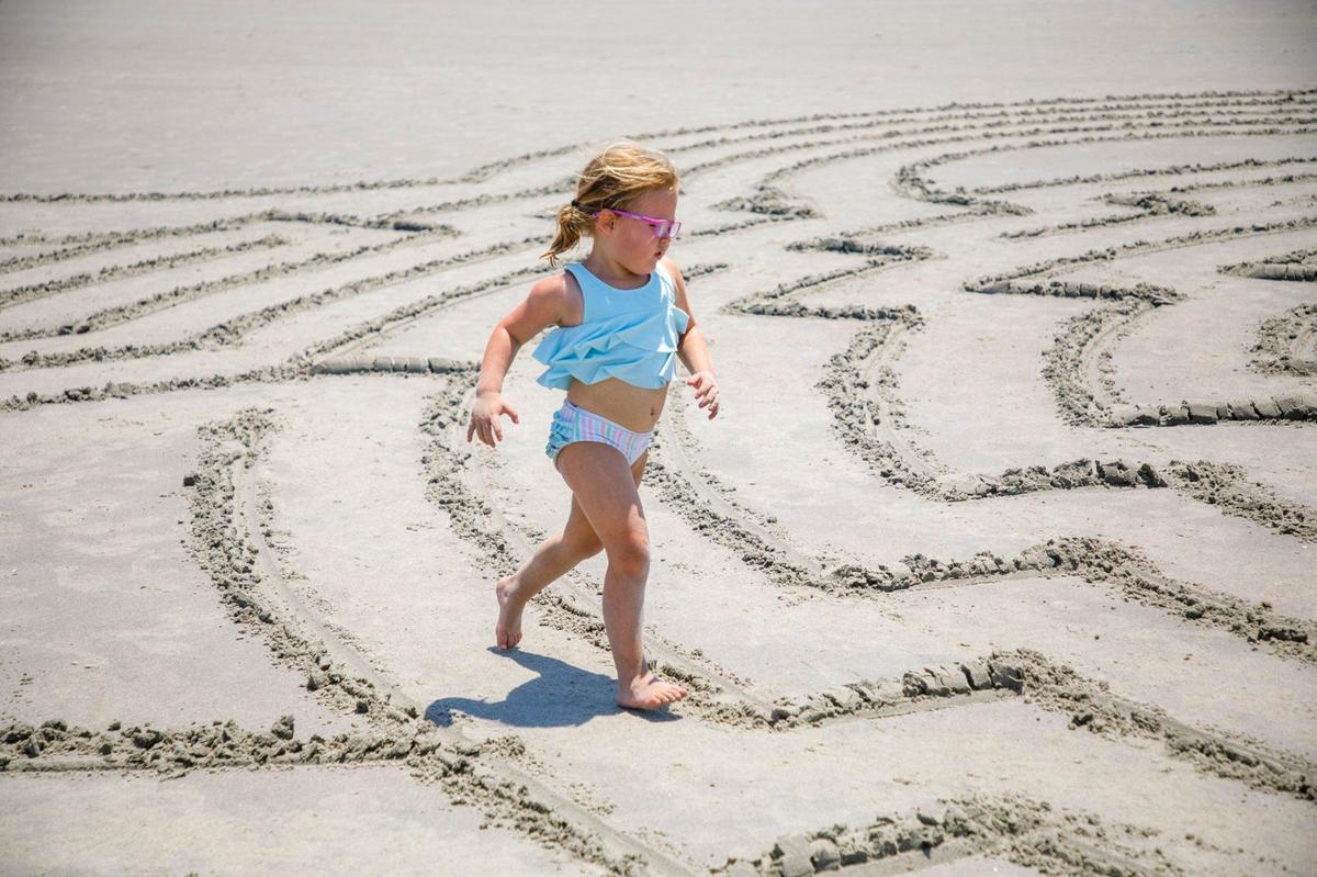 Savannah Cope, age 5, runs through a sand maze on Sunset Beach, N.C. Hunter Gibbes, known locally as “Sunset Beach Maze Man,” has been making mazes at Sunset Beach, N.C. for nearly 20 years. The sand artist makes up the designs on the spot. Vacationers and locals rush to complete the mazes he creates before the tide comes in and creates a clean slate for his next artwork. Aug. 1, 2024.
