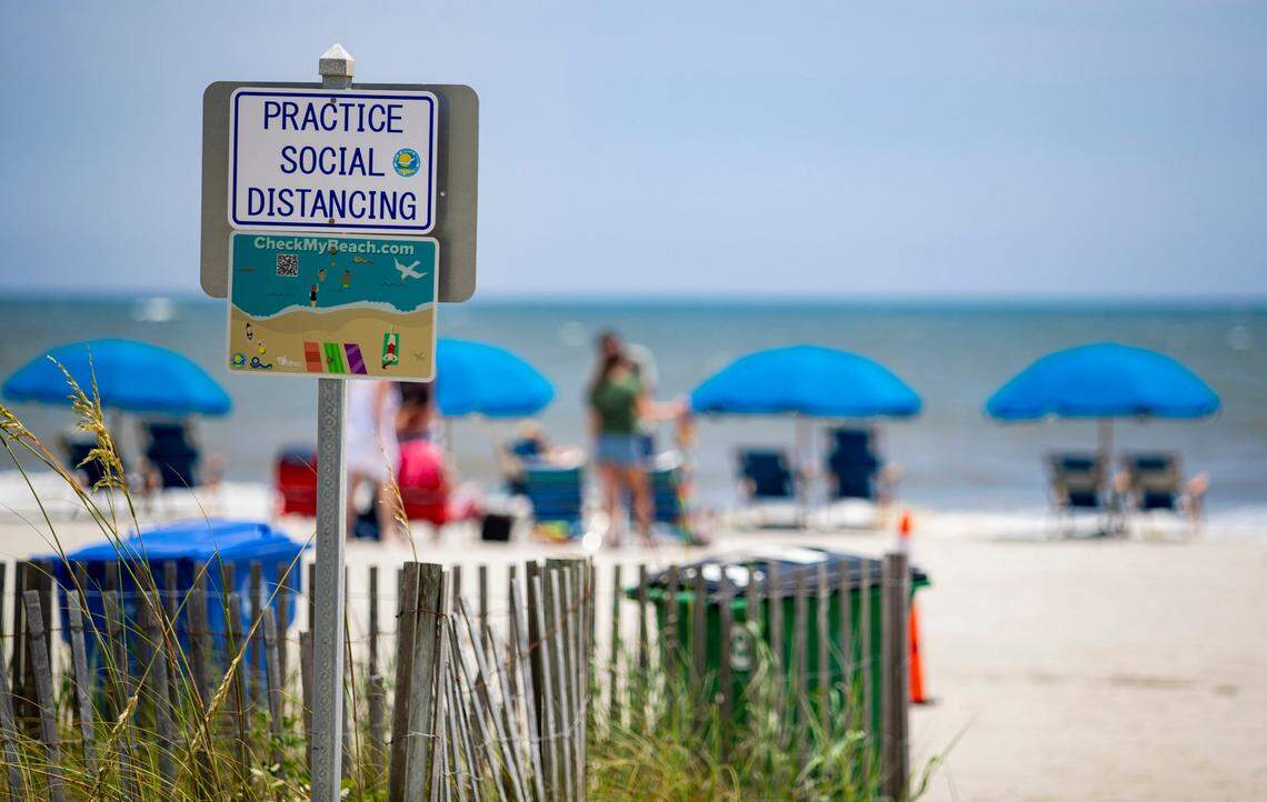 A sign advises beachgoers to “practice social distancing” along the beach in Myrtle Beach Monday afternoon as health officials report 112 new coronavirus cases on Monday.