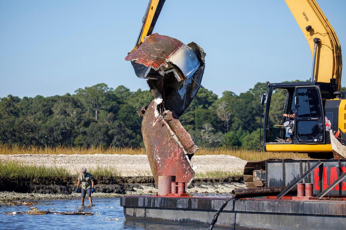 Whit Jones, a member of Wounded Nature Working Veterans, picks debris from the water as locale volunteers from Black Water Dredging lift portions of a sailboat out of the Calabash River. Abandoned boats litter the waterways throughout Horry County, S.C. The Department of Natural Resources is partnering non-profit conservation groups and local businesses to begin removing the derelict vessels from local waterways. Oct. 20, 2021.