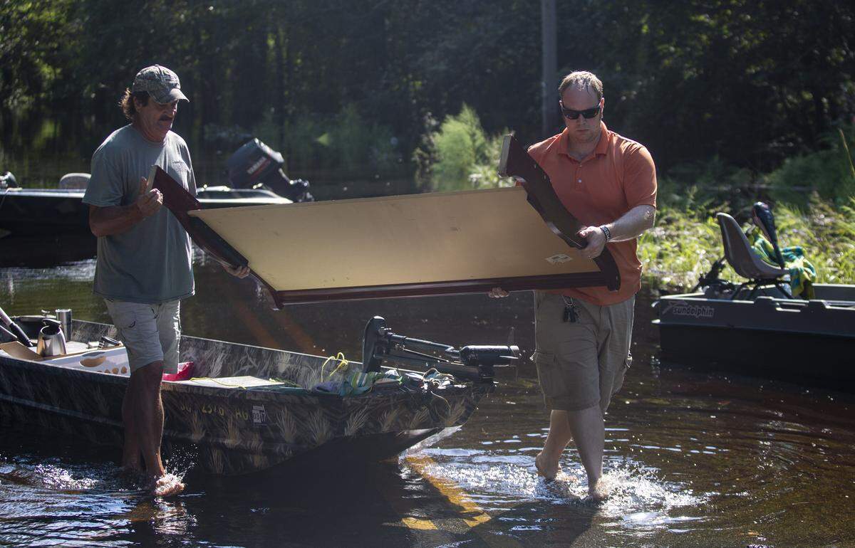 Conway area residents Daniel Edmonds (L) and Ted Hayden pull a headboard out of a boat after retrieving it from a home on Pitch Landing Drive. Rising flood waters have made many homes in the area inaccessible by car, so residents have begun launching boats to retrieve personal belongings and valuables.
