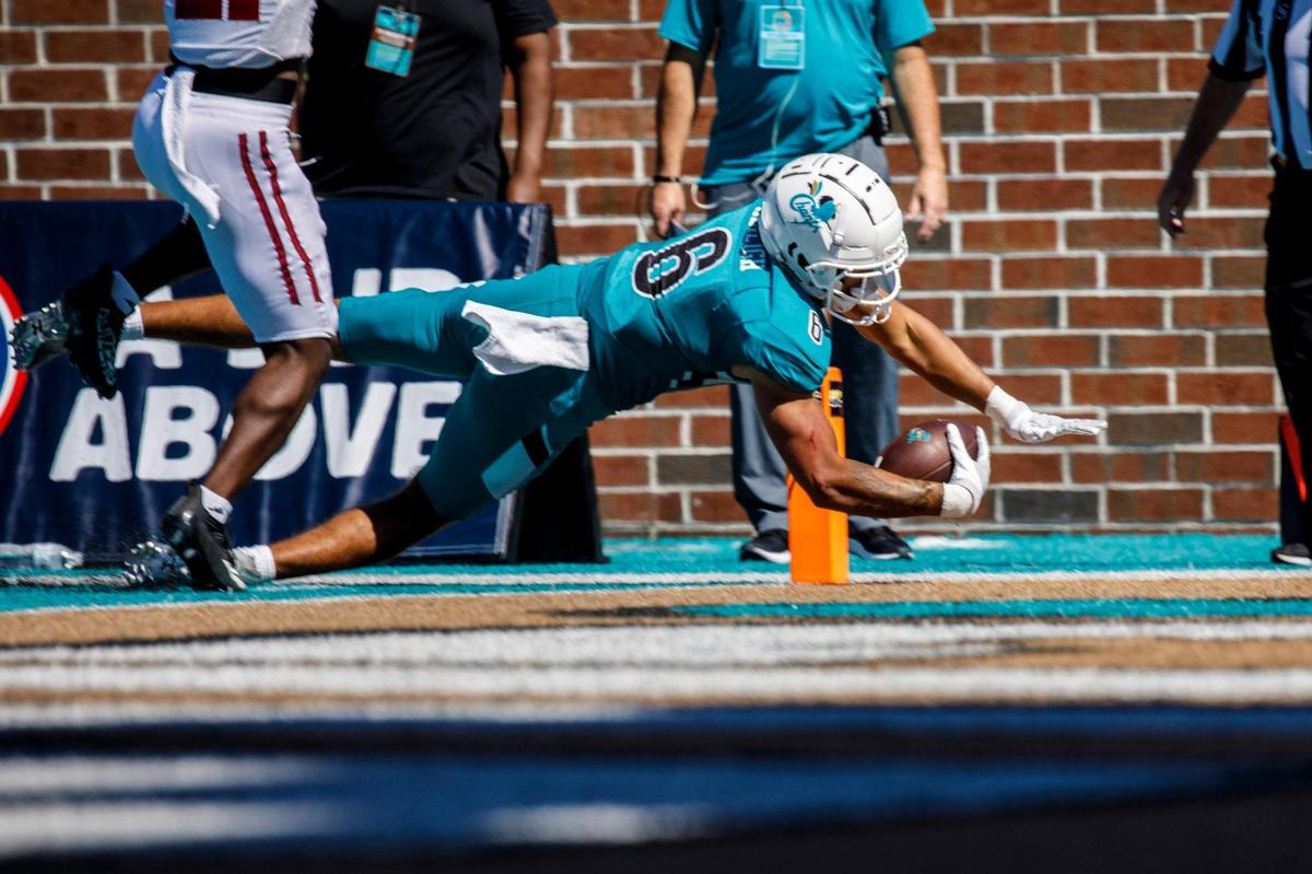 Coastal’s Jaivon Heiligh scores against U.Mass after a pass reception on Saturday. Coastal Carolina, ranked 17, defeated Massachusetts on Saturday at Brooks Stadium in Conway SC. Spectators were encouraged to wear teal for a “teal out” promotion. Aug. 11, 2021.