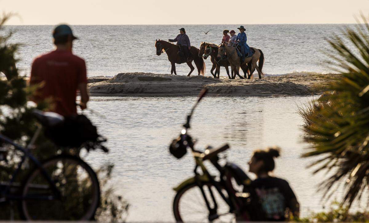A couple fish in Midway Swash as hundreds of horses and their riders hit the beach this morning for the American Heart Association 44 annual Beach Ride event.  Nov. 8, 2025.