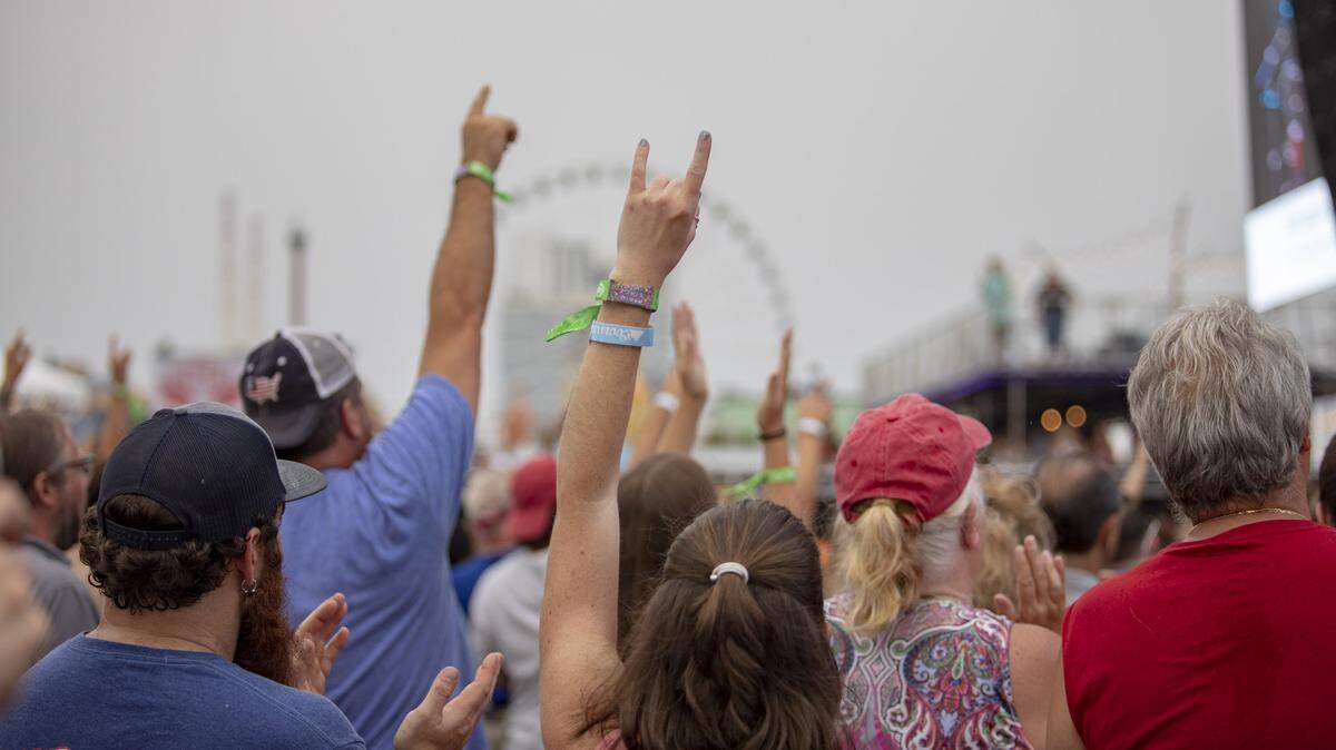 CCMF attendees raise their hands as Gyth Rigdon performs the National Anthem Thursday afternoon at Carolina Country Music Fest.