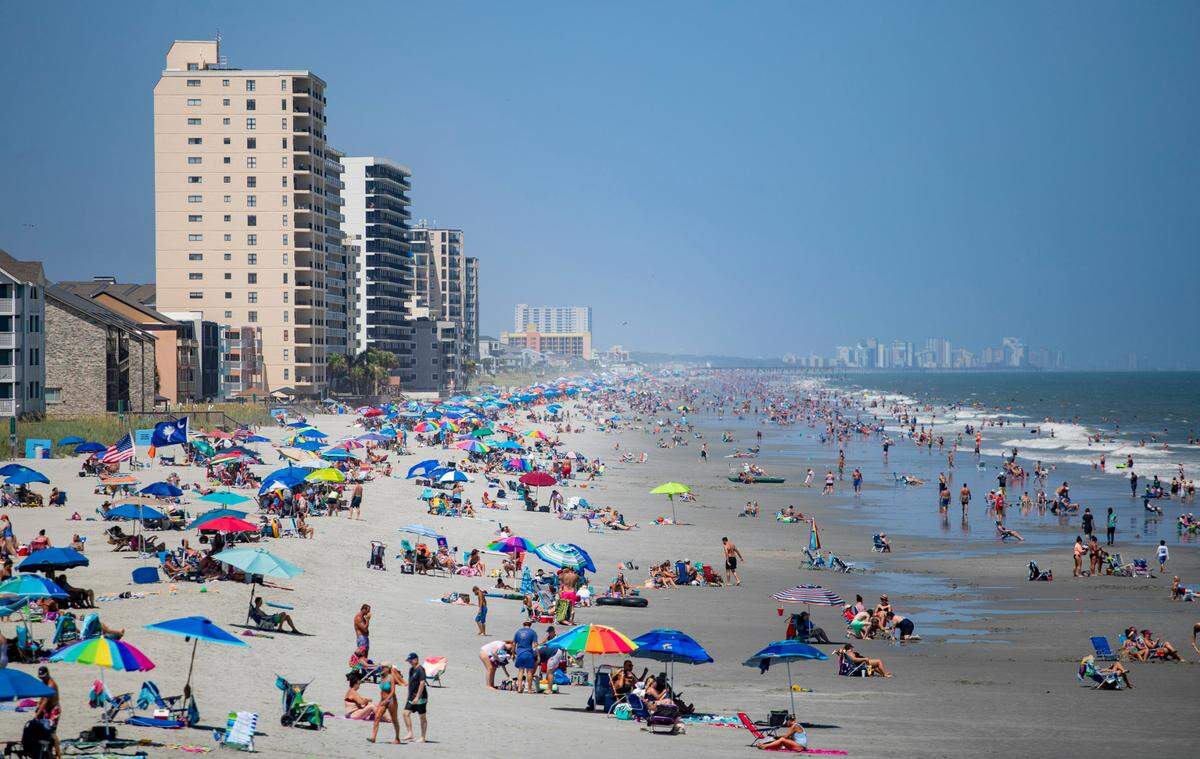 People walk along the beach Sunday afternoon in Garden City as Tropical Storm Isaias approaches the coast, and the coronavirus pandemic continues to spread. At least 91,257 people have tested positive for the coronavirus in South Carolina and 1,709 have died, according to state health officials.