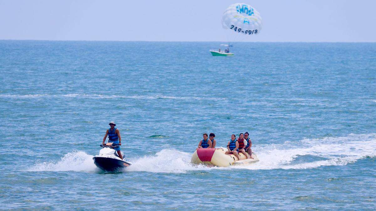 A group of people enjoy the water on a rented banana boat being towed by an Aloha Watersports employee driving a jet ski on May 29, 2025.