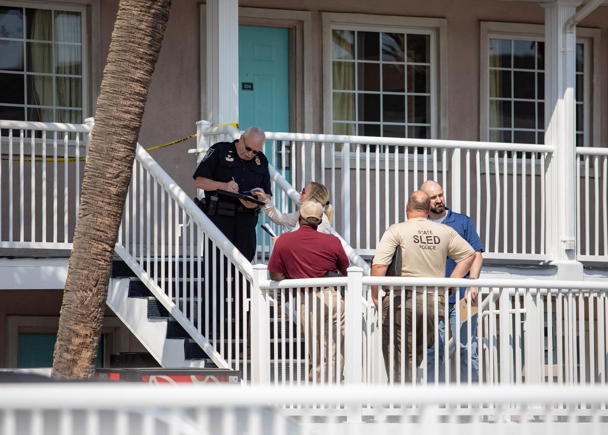 Law enforcemenet members gather on the steps of the Lancer Motel in Myrtle Beach, where a person wanted for attempted murder in Upstate South Carolina was found dead Thursday afternoon according to Myrtle Beach police. The motel is located on North Kings Highway.