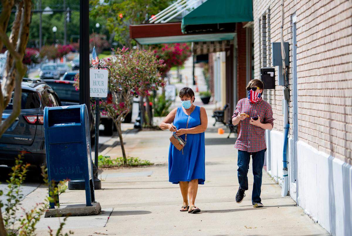 Pedestrians wear masks while walking in downtown Conway on Monday afternoon.