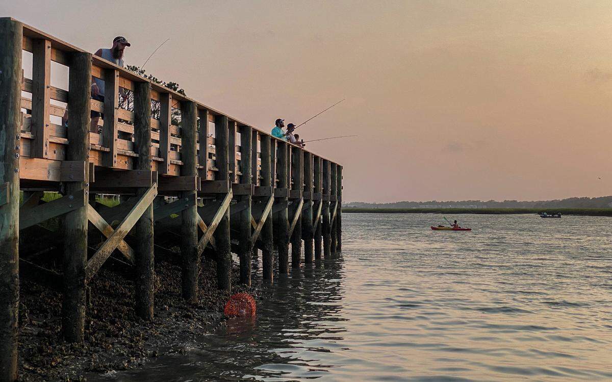 Fishermen line the piers of Hog Inlet in the Cherry Grove section of North Myrtle Beach during low tide. Aug. 11, 2021.