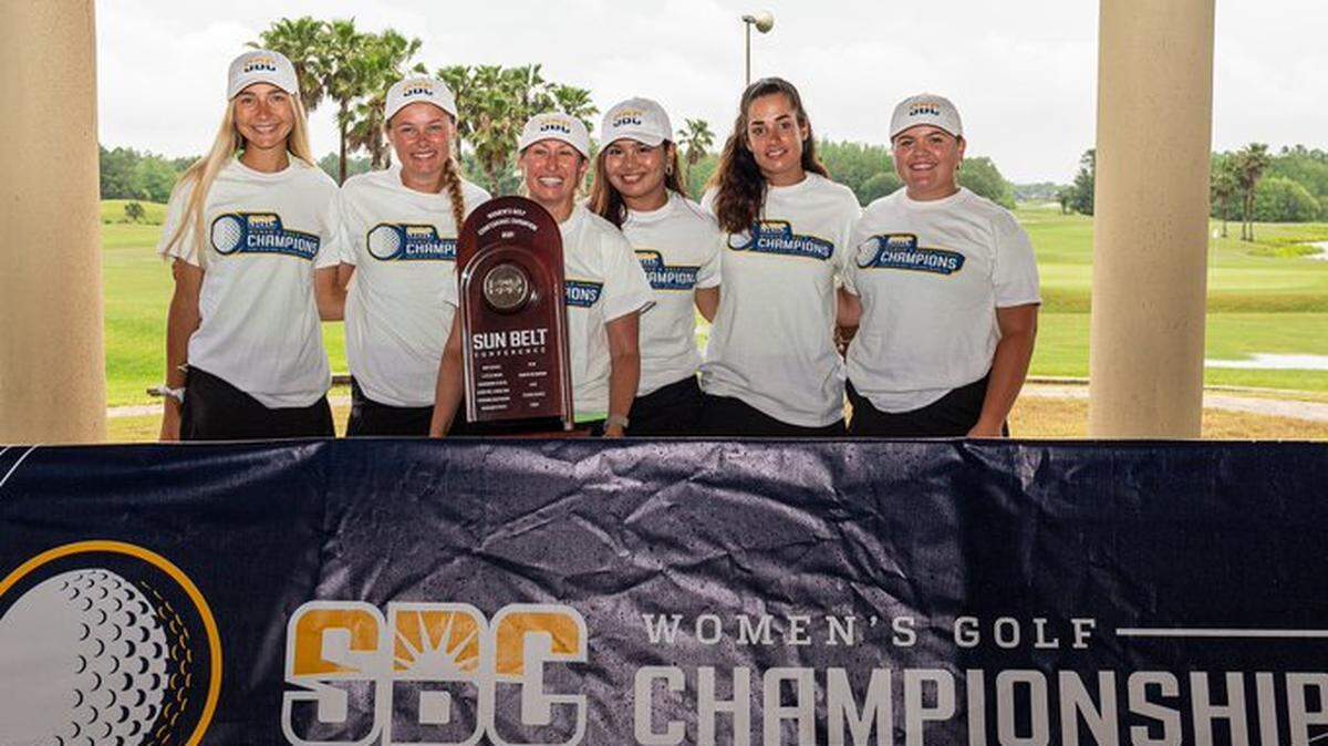 The Coastal Carolina women’s golf team and coach Katie Quinney pose with the Sun Belt Conference championship trophy Tuesday at LPGA International in Daytona Beach, Florida.