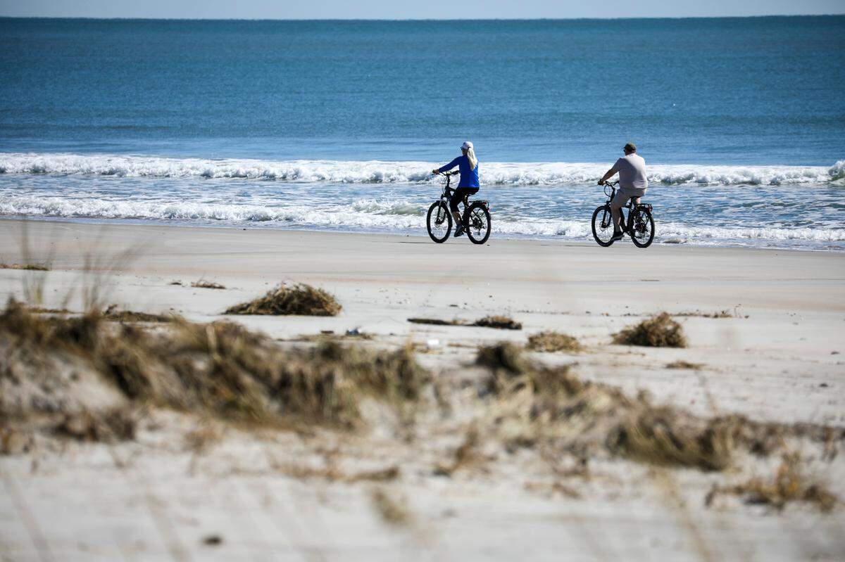 Flattened dunes on the North end of Huntington Beach State park give an unencumbered view of bicyclists riding past. Volunteers and state park workers from around South Carolina have worked to repair Huntington Beach State Park for days since Hurricane Ian brought damaging flooding to the popular attraction. October 5, 2022.