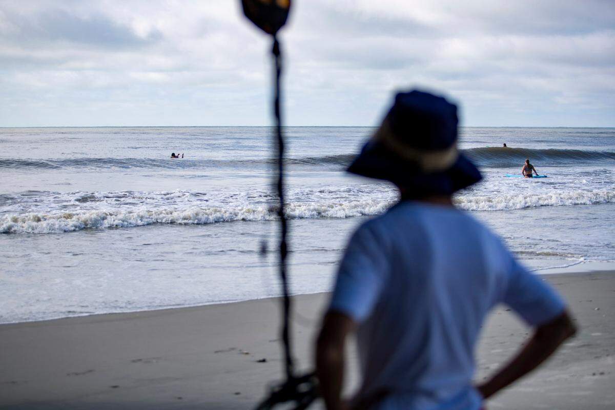 Murrells Inlet resident Lydia Hogan looks out over the ocean while surfers take to the waves near Springmaid Pier Tuesday morning in the wake of Tropical Storm Isaias.