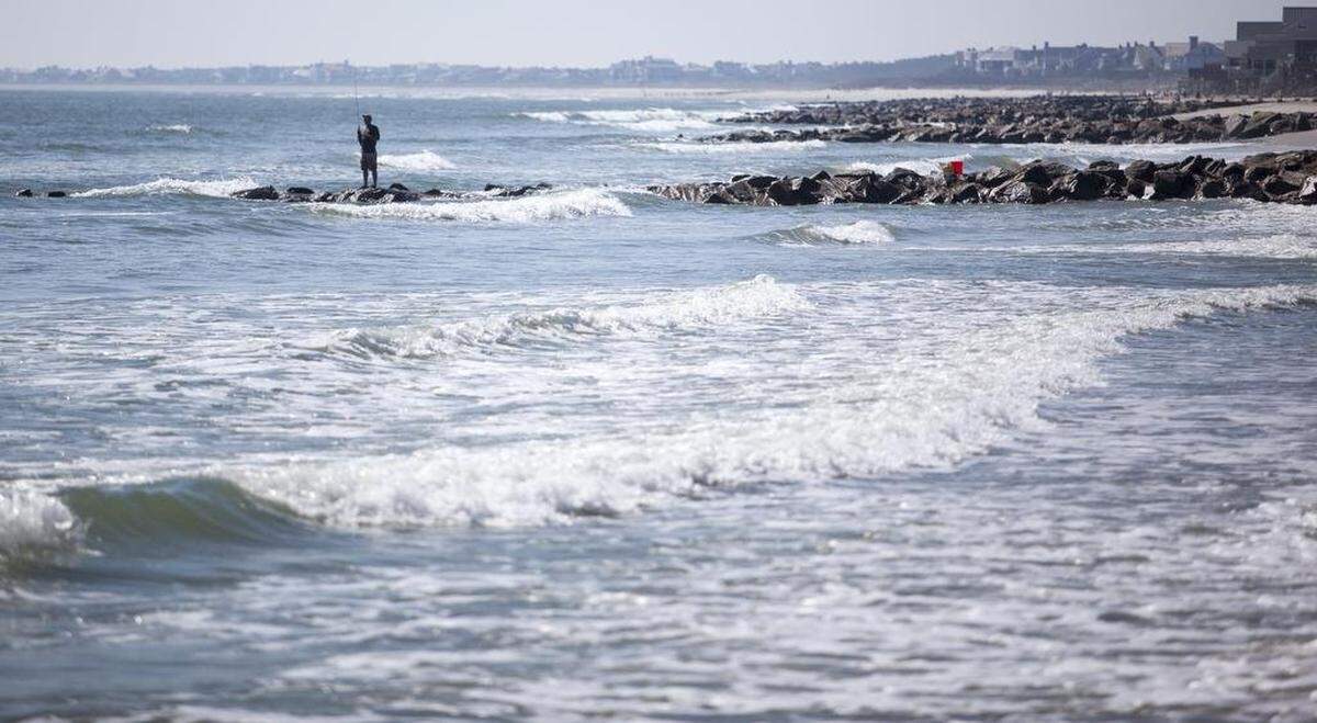 A fisherman stands on a rock groin in Pawleys Island that is supposed to help retain sand on the town’s beaches. Groins are supposed to help protect beaches from erosion, but critics say they don’t work.