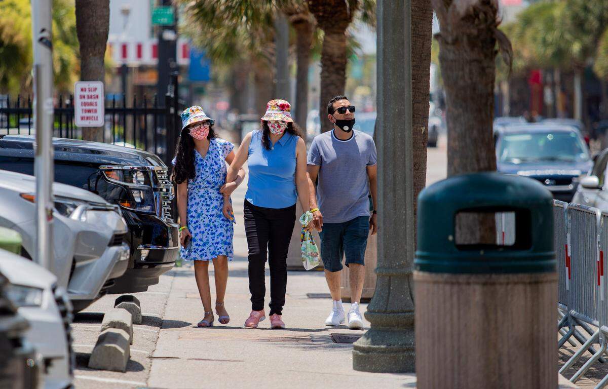 A masked family walks along Ocean Boulevard in Myrtle Beach. Local politicians and health officials debate whether masks are effective against the coronavirus.