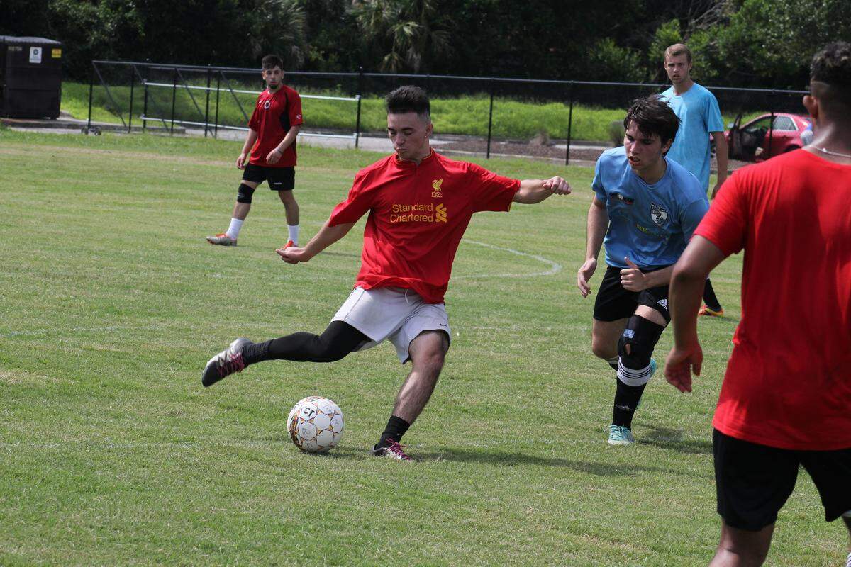 A member of the Legends soccer team (in red) takes a shot against Chicago FC (in blue) during a charity soccer tournament raising money to send soccer equipment to kids in Costa Rica and Nigeria.